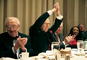 Seated next to retired U.S. Supreme Court justice John Paul Stevens, Judge William J. Bauer (center) of the 7th U.S. Circuit Court of Appeals raises his hands in celebration of his 88th birthday at The Chicago Bar Association’s 15th annual Justice John Paul Stevens Awards Luncheon at The Standard Club. 