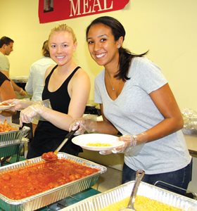 Loyola University Chicago School of Law first-year students Sarah Wittenauer (left) and Khari Fischer serve meals to residents at the Lawson House YMCA during 1L orientation.